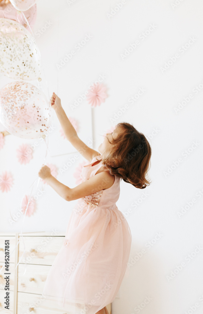 Naklejka premium Little girl wearing pink dress with balloons. Styled home birthday party