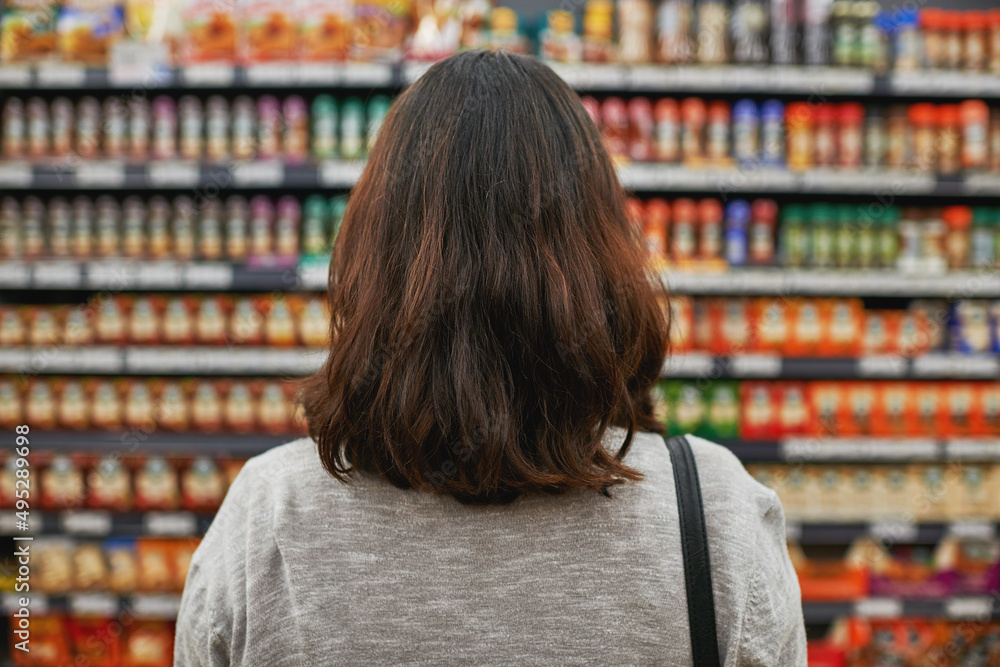 Finding the best products at the best price. Rear view shot of a woman browsing for items in a grocery store.
