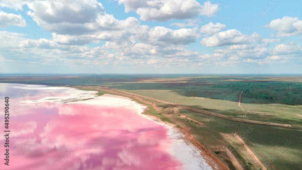 Panoramic view amazing landscape of pink lake coast with cloudy blue sky. Kherson region of Ukraine
