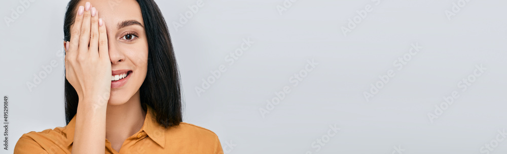 Woman closing eye with her hand for checking vision, isolated on grey background. Vision test concept for adult Woman closing eye with her hand for checking vision, isolated on grey background. Vision test concept for adult