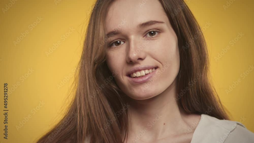 Young adult caucasian woman is posing on a bright yellow background in studio