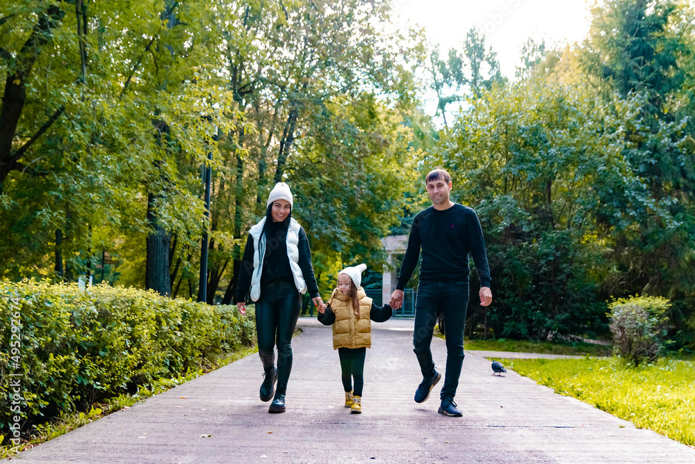 Obraz premium A woman and a man and a child are walking in the park. Summer park. Green trees. The concept of a young family.