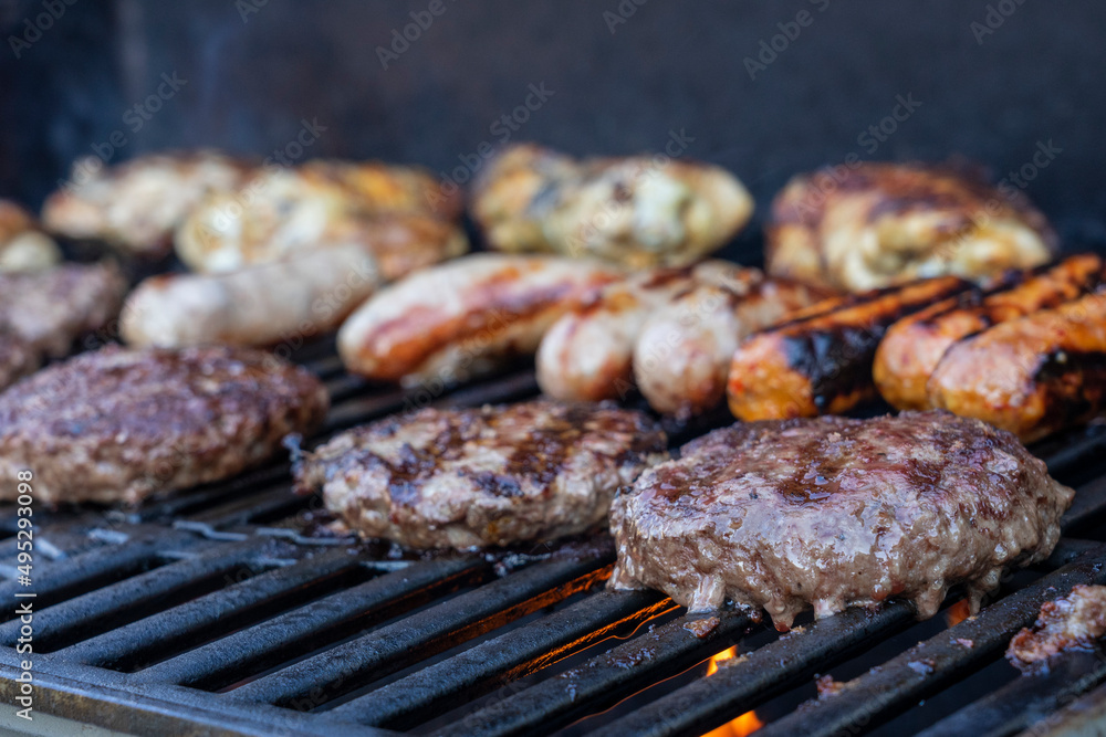 Burgers and sausages cooking on a BBQ grill