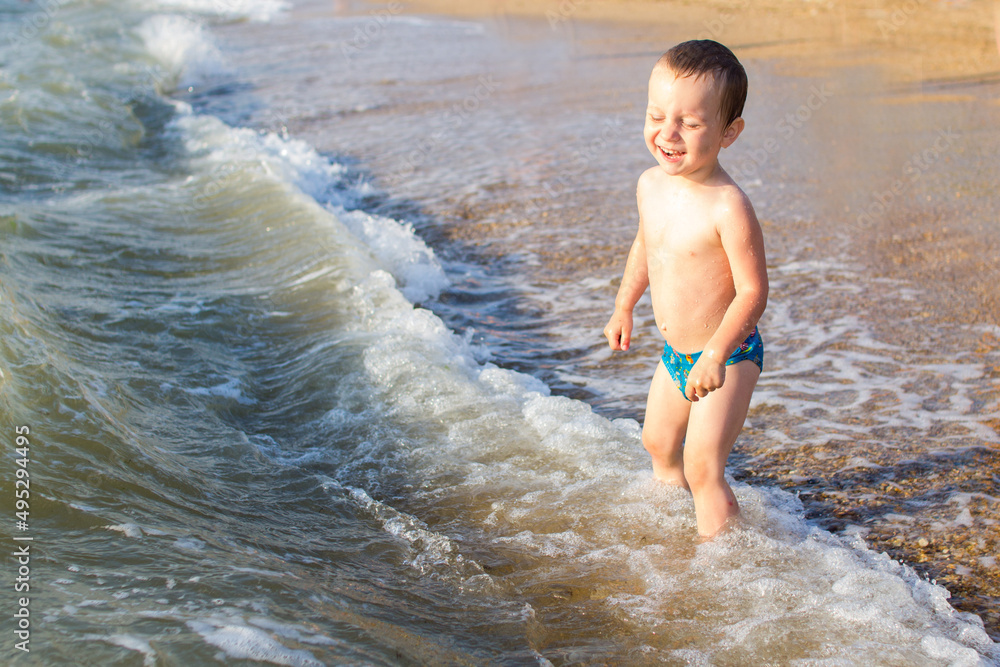 Fototapeta premium a little boy having fun in the sea on the waves