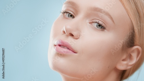 Extreme close-up beauty portrait of young beautiful blond European woman on blue background   Skin care cosmetics commercial concept