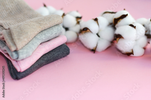 Fototapeta Naklejka Na Ścianę i Meble -  4 pairs of multicolored cotton socks and a branch of cotton on a pink background. the concept of clothing made of natural materials