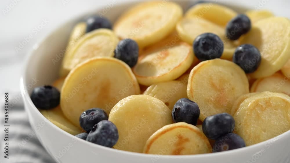 Step by step. Freshly made mini pancake cereal with fresh blueberries in a white bowl. Step by step. Freshly made mini pancake cereal with fresh blueberries in a white bowl.