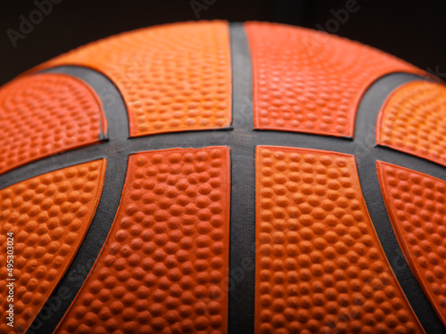 Macro shot. Details of a basketball ball on a black background. Sports, sports games, champions league, training, hobby, professional sports, healthy lifestyle. © Anton