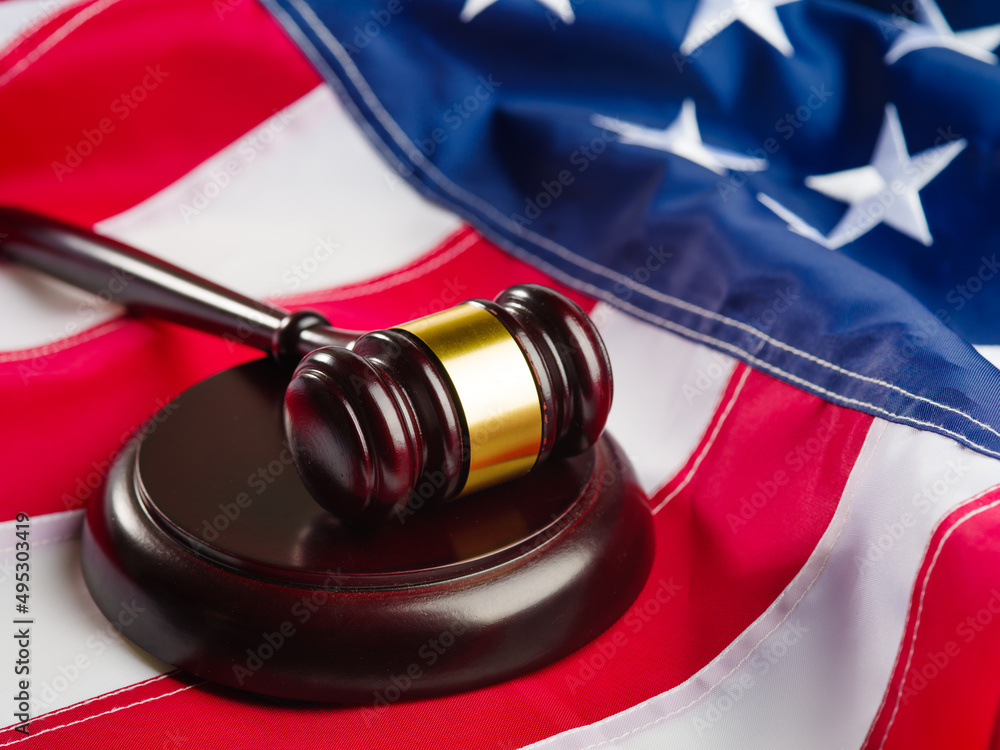 The national flag of the United States of America and the judge's wooden gavel. Close-up. Patriotism, justice, justice, rule of law. Color image. There are no people in the photo. Banner.