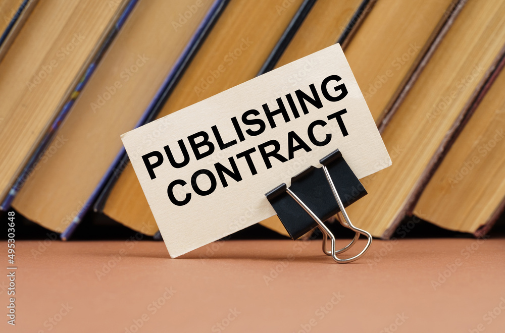 On the table against the background of books is a business card with the inscription - Publishing contract