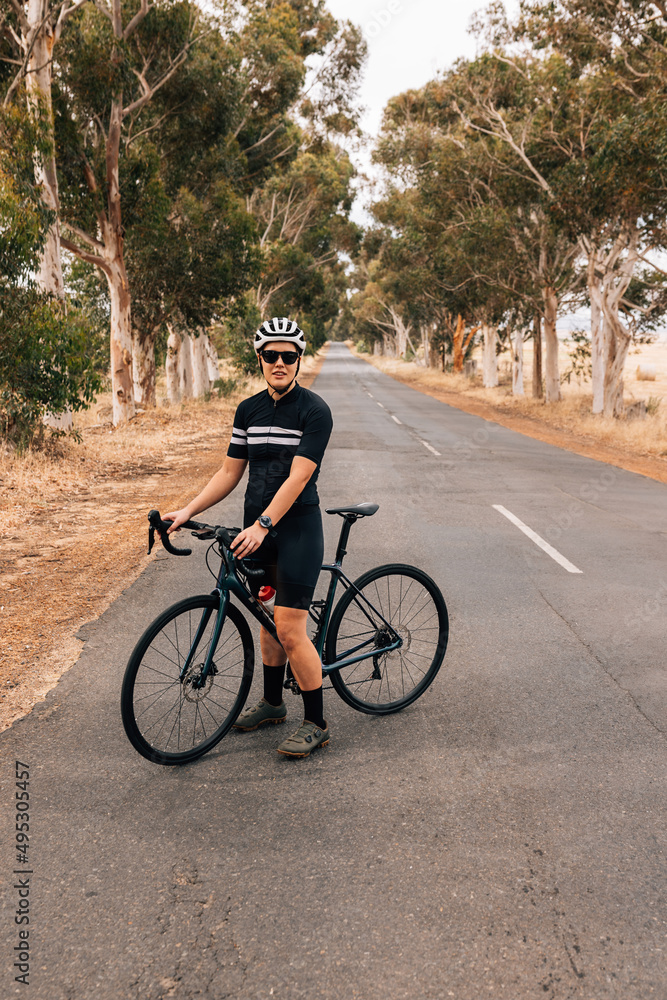 Professional woman cyclist standing with bike on a road Professional woman cyclist standing with bike on a road