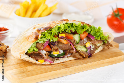 Döner Kebab Doner Kebap slice fast food in flatbread with French Fries on a wooden board