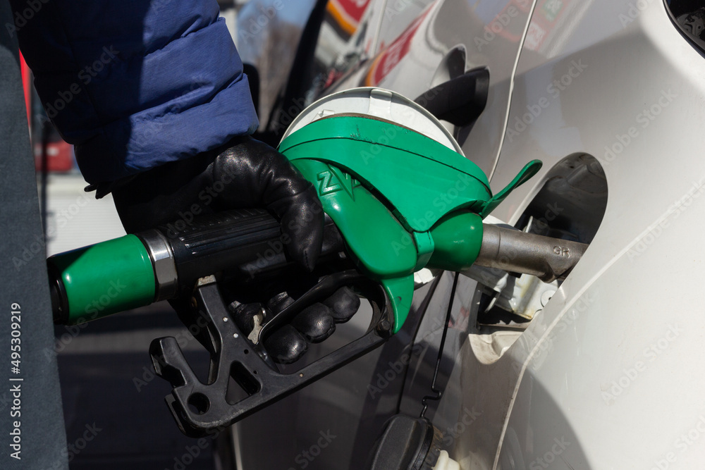 Closeup of a person filling their tank with fuel at a gas station.