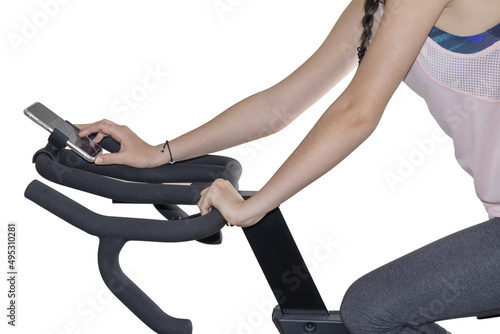 fitness machine with arm view of young girl on exercise bike using smartphone with white background for copy space