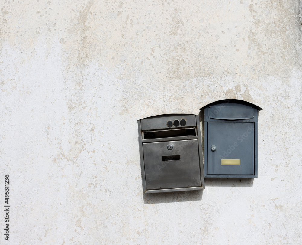 Two metal mailboxes hang on a light, dirty wall. Old mailboxes. Two metal mailboxes hang on a light, dirty wall. Old mailboxes.