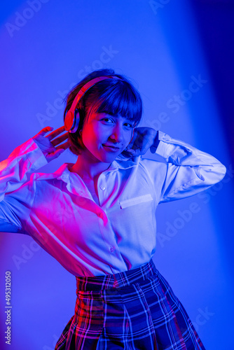 High Fashion model woman in colorful bright neon blue and purple lights posing in studio. Portrait of beautiful woman with trendy glowing make-up. Art design vivid style   