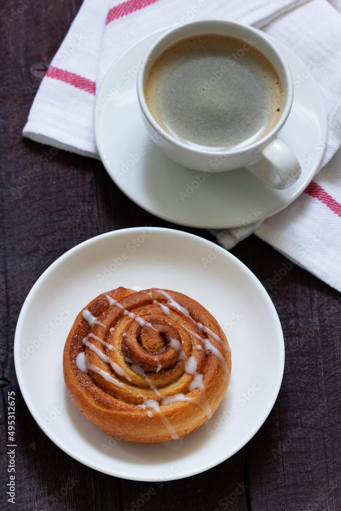 Cinnamon buns with icing served with coffee. Rustic style.