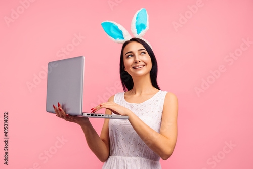 Wall Mural Thoughtful woman in bunny ears holding laptop, video call, shopping online in st