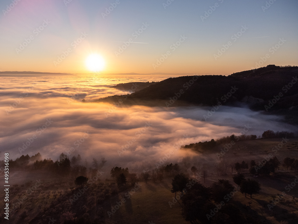 Drone view of Umbria valley Italy above a sea of fog at sunset Drone view of Umbria valley Italy above a sea of fog at sunset