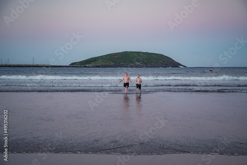 Kids walking out of water after swim at the beach with beautiful twilight sky at Coffs Harbour, Australia photo