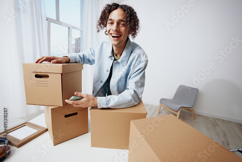 guy with curly hair with a phone in hand with boxes moving sorting things out
