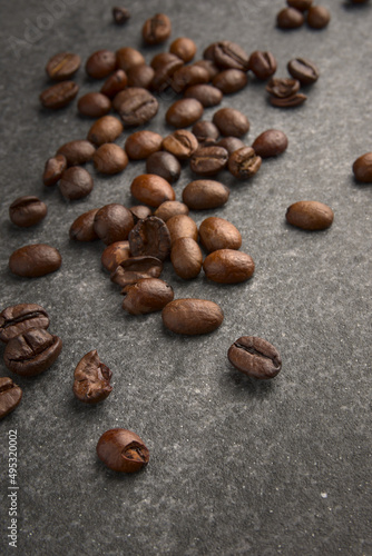 Brown aromatic roasted coffee beans on a gray stone background.