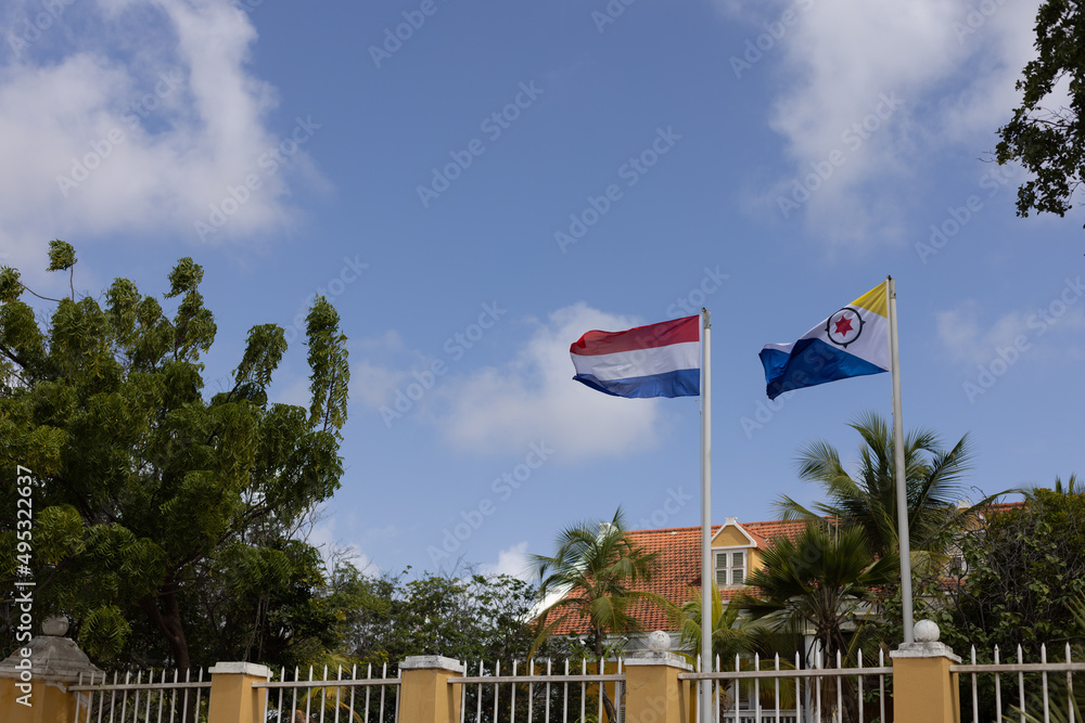 Flag of Bonaire and Netherlands flying in the wind near house.