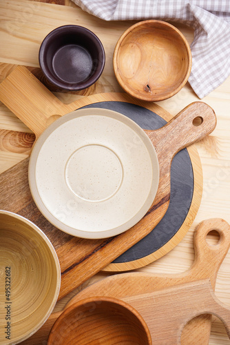 Dishes for serving and eating meals on a wooden background, top view. Modern ceramic and wooden crockery, trendy tableware.