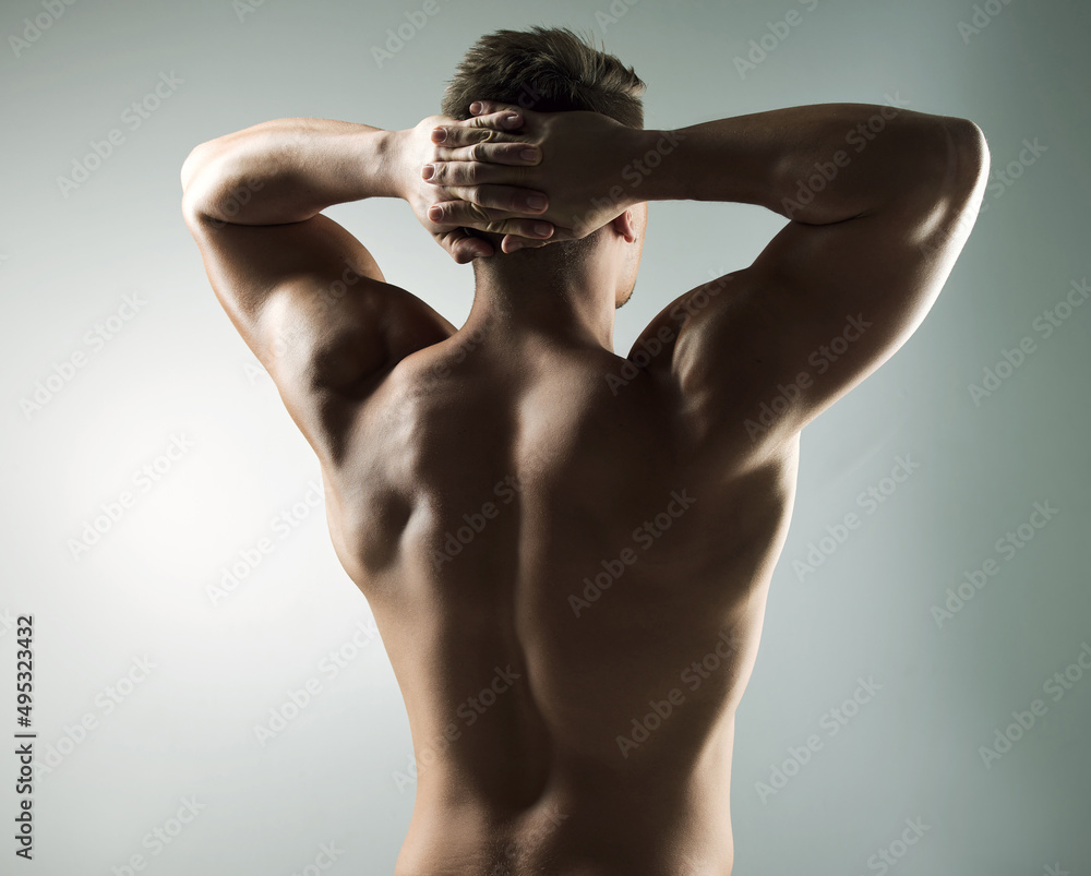 Earned, not given. Studio shot of a muscular young man posing against a grey background.