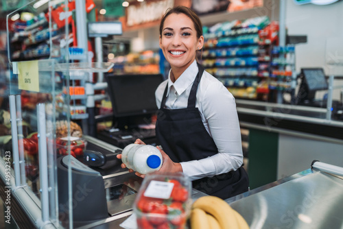 Beautiful young female cashier working at a grocery store. photo
