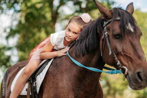 The girl lies on a horse and hugs her. Rehabilitation of a child through contact with a horse.