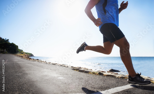 Running is a way of life. Low angle view of a runner next to the ocean.