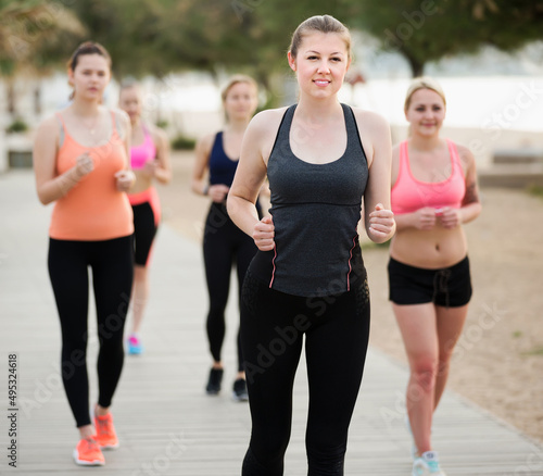 Positive women running during outdoor workout on city seafront