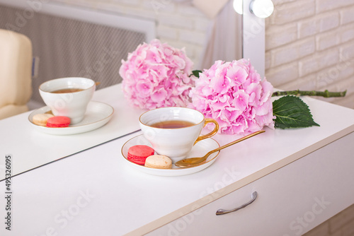 
Client place in hairdressing beauty salon with cup of tea, macaroons and flower