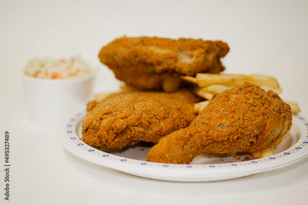 Three pieces of fried chicken and fries and cleslaw salad in studio lighting Three pieces of fried chicken and fries and cleslaw salad in studio lighting