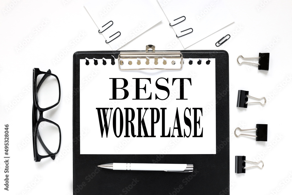 BEST WORKPLASE. white paper text on black folder near glasses BEST WORKPLASE. white paper text on black folder near glasses