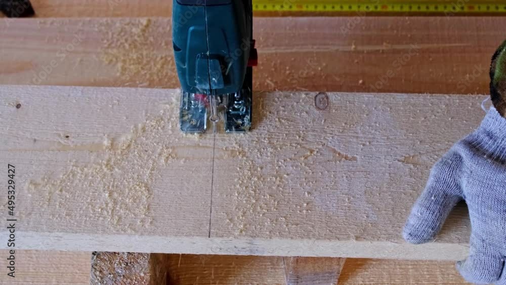 Sawing a board with an electric jigsaw in close-up. Carpentry on wood with a tool, sawdust flies, the saw cuts in a straight line. Home repair with your own hands, a sawmill. Slow motion Sawing a board with an electric jigsaw in close-up. Carpentry on wood with a tool, sawdust flies, the saw cuts in a straight line. Home repair with your own hands, a sawmill. Slow motion