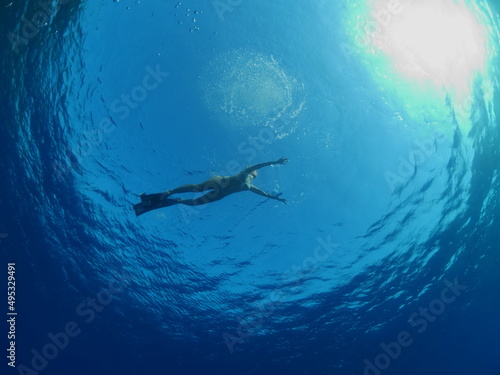 apnea free diver underwater with rocks and sun shine and beams and sun rays