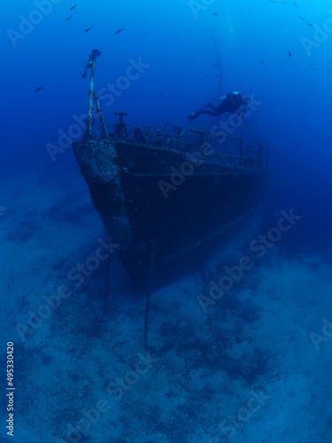 scuba divers exploring and discovering the ship wreck underwater deep sea bottom metal on ocean floor