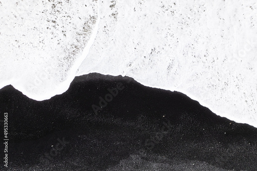 An aerial view of a black beach in Iceland. Waves and black sand on the beach. View from a drone.