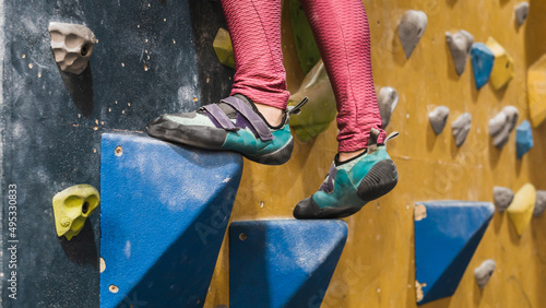 Feet of a person on a climbing wall.