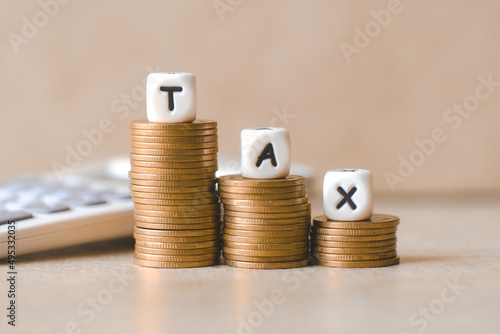 Obraz na plátně Block word tax on money and calculator on wooden background, TAX on stacked coins financial Tax concept