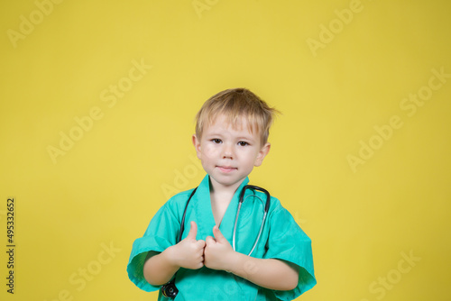 Portrait of little caucasian boy dressed in doctors showing thumb up gesture