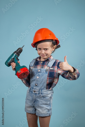 Adorable caucasian child in orange safety helmet,holdings crewdriver at hands. photo