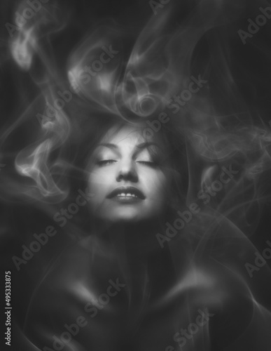 Beautiful sensual woman with closed eyes wrapped in smoke or mist in black and white