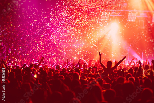 Fotografia A crowded concert hall with scene stage in red lights, rock show performance, wi