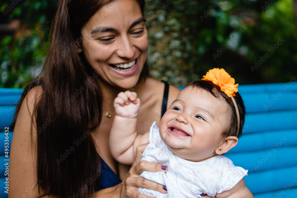 young latina mom with her smiling baby playing outdoors Stock Photo | Adobe Stock