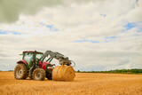 His farm is well-kept. Shot of a farmer stacking hale bales with a tractor on his farm.