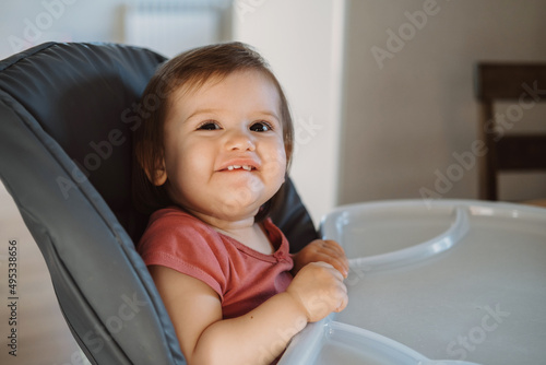 Portrait of a little baby girl smiling sitting in a high chair. Beautiful girl. Baby care.