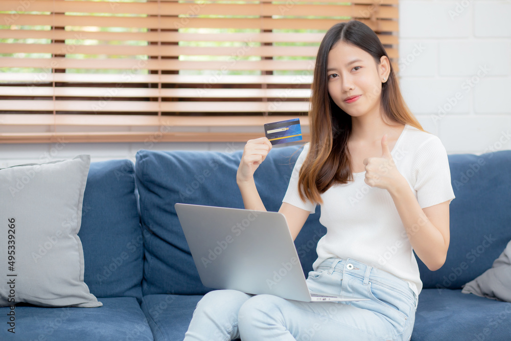 Young asian woman sit on sofa using laptop computer shopping online with credit card buying to internet, happy girl payment with e-business on couch, purchase and payment, business concept. Young asian woman sit on sofa using laptop computer shopping online with credit card buying to internet, happy girl payment with e-business on couch, purchase and payment, business concept.